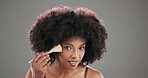Face, brush and black woman in studio, makeup and foundation on grey background. Portrait, happy person and model with cosmetics tools, aesthetic and skincare with beauty, grooming and confidence