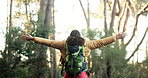 Woman, back and hiking with open arms in nature for fresh air, freedom or outdoor adventure. Female person, hiker and walking with backpack in relief for trekking journey or natural scenery in forest