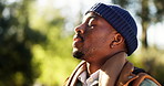 Breathing, fresh air and man in woods, peace and wellness for traveller in nature, happy or holiday. Outdoor, hiker and black person with smile on break, calm and mindfulness on vacation in forest