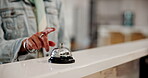 Hotel, reception desk and hand with bell to press, request help and urgent attention for service. Closeup, person and buzzer while waiting for booking, reservation or concierge signal for hospitality