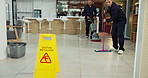 Janitor, teamwork and office with caution sign, hygiene service and wet floor for disinfection. Attention, safety and warning for risk, cleaner and group for maintenance, tile polishing and equipment