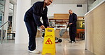 Janitor, team and office with caution sign, hygiene service and wet floor for disinfection. Attention, safety and warning for risk, teamwork and cleaner for maintenance, tile polishing and equipment