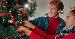 Christmas tree, happy and couple in home with decoration for holiday, vacation and festive season. Interracial, love and man with woman hanging ornaments for xmas tradition, bonding and celebration