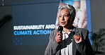 Stage, speaker and senior woman with mic, talking and seminar for global warming and climate change. Speech, environmental Economist and discussion for alternative energy, person and sustainability