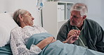 Holding hands, hospital bed and senior couple talking for comfort, support and empathy for recovery. Healthcare, marriage and mature man and woman visit for compassion, care and help for wellness