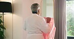 Mature woman, clothes and choice with mirror, smile and dance for fashion, style and morning start. Person, happy and decision with outfit, garment and throw shirt in bedroom for wardrobe in house