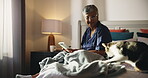Senior woman, book and cat in bedroom for daily journal, reminder and word puzzle. Smile, elderly person and writing for brain games, creative activity and to do list by bonding with animal at house