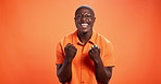 Face, excited and black man in studio, smile and celebration on orange background. African person, portrait and happy model with victory, winner or success with prize, wow and achievement with energy