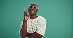 Face, peace sign and black man in studio, fashion and sunglasses on green background. African person, hand gesture and happy model with eyewear, stylish clothes and casual outfit with confidence