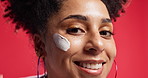 Cream, skincare and face of woman apply in studio for skin hydration, wellness and facial care. Dermatology, spa and portrait of person with moisturizer, lotion and creme for health on red background