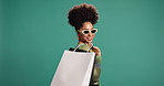 Face, shopping bag and happy woman with sunglasses for fashion, sales and discount. Smile, shopaholic and African customer with gift for Black Friday, promotion and mockup space on studio background