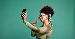 Peace sign, selfie and social media with black woman on green background for live streaming. Blowing kisses, emoji hand gesture and video recording with influencer in studio for content creation