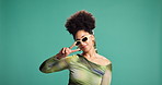 Face, peace sign and woman in studio, sunglasses and fashion on green background. Portrait, happy person and model with hand gesture, thumbs up or stylish clothes with shades, casual outfit or gen z 