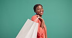 Face, happy black woman and shopping bag for fashion, discount sale or deal on green background. Shopaholic buyer, laugh or customer with gift for promo, space or excited for retail bargain in studio