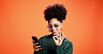 Funny, phone and sunglasses with black woman on wall background for reaction to social media post. Fashion, laughing  and shades with happy African person in orange studio for mobile communication
