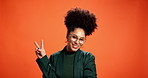 Face, peace sign and smile with black woman on wall background as social media influencer. Afro, emoji reaction and glasses with happy African person in orange studio for post as content creator