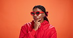 Studio, thinking and woman with sunglasses, fashion and trendy accessory for influencer and serious. Orange background, contemplating and black person with shades, mockup space and colorful jacket