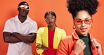 Studio, woman and confident with clothes, group and celebrity fashion designer with smile and happy. Orange background, stylist and people with trendy outfit, face and pride with shades and creative