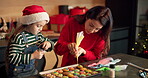 Decorating, biscuits and mom with child in home, learn or cream for dessert on Christmas in kitchen. Teaching, daughter and woman with sprinkles for cookies, baking and snack for festival in house