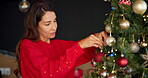 Woman, hang and decorations on tree for Christmas tradition, celebration and festive season. Smile, female person and preparation with ornaments, sparkle aesthetic and event on xmas holiday at house
