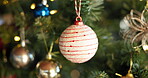 Christmas, festive and ball with decoration on tree for sparkle, bauble or holiday season. Merry xmas, tradition and December celebration with ornament in living room of home for vacation and closeup