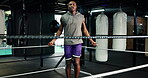 Active, black man and jump with rope at gym for fitness, cardio exercise or prepare for boxing match. Male person, skipping and equipment for workout, endurance training and performance for challenge