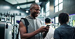 Athlete, man and laughing with phone at gym for fitness meme, comic workout video and online joke. Happy, person and sports bag with smartphone at health club for funny message and ready to exercise