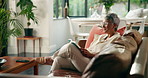 Senior, woman and reading a book on sofa for story, knowledge and retirement hobby. Happy, reader and relax with literature novel in home for fiction bestseller, peaceful and wellness in living room
