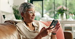 Mature woman, texting and phone on sofa, thinking or scroll for contact, chat or notification in home. Person, smartphone and click on mobile app, relax or check post with social network at apartment