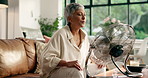Senior woman, menopause and breathing with fan for hot flashes in relax for treatment at home. Mature, female person or smell with blowing air for relaxation technique, candle incense or calm remedy