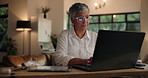 Mature, woman and typing with laptop in home for project deadline or schedule tasks at night. Female person, freelancer or remote worker in late evening on computer for overtime or research at house