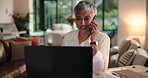 Laptop, phone call and smile with freelance woman at desk in living room of home for remote work. Communication, computer and happy with mature person in apartment for mobile discussion at night