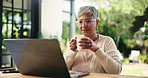 Drinking coffee, laptop and remote work with mature woman in home office for small business research. Beverage, computer and glasses with freelance person typing information in apartment for startup