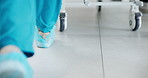 Feet, gurney and walking in hospital with medical team for emergency operation or surgery from back. Healthcare, insurance and teamwork with group of doctors in hallway of clinic for procedure