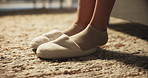 Home, plush slippers and woman in bedroom, feet and fashion with comfort, carpet and morning. Closeup, apartment and person with shoes, footwear on rug and start day with bed rest and waking up