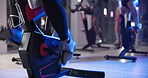 Feet, cycling class and people in gym for biking workout, health or leg muscle training. Fitness, coach and group with personal trainer on bicycle machine for cardio exercise in sports center.