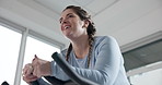 Low angle, stationary bike and woman exercise for fitness, burn calories and lose weight. Gym, happy person and indoor cycling for cardio training, endurance workout and body strength for health