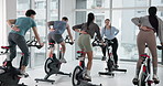 Cycling class, instructor and people in gym for fitness, workout or body training with group. Health, energy and spinning coach with athletes on bicycle machine for cardio exercise in sports center.