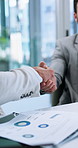 Businessmen, documents and meeting with handshake for corporate deal or performance at office desk. Male people, employees or colleagues shaking hands with paperwork for business review or agreement