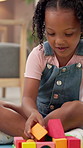 Toys, playing and kid in house for game, creativity or fine motor skills on floor. African child, girl and educational building blocks for learning, problem solving or cognitive development in home