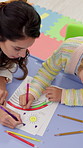 Coloring, education and teacher with child in classroom for learning, development or fine motor skills. Top view, lesson and female educator with girl kid for fun activity together at kindergarten.