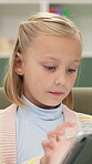 Child, girl and play on tablet at house for learning, online games and website for education. Kid, digital and app for study, streaming videos and language reading for elearning application in lounge