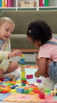 Building blocks, education and growth with friends in office for cognitive or problem solving skills. Creative, development and puzzle with girl students on classroom floor for game, study or therapy