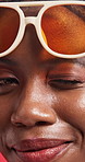 Wink, fashion and face of black woman with sunglasses for trendy, funky or colorful style. Flirt, laugh and portrait of African female person from Nigeria with cool eyewear by studio background.