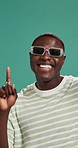 Face, dancing and black man in studio, smile and celebration on green background. Portrait, African person and model with energy, movement and sunglasses with fashion, stylish clothes and happiness
