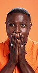 Shock, cover mouth and face of black man in studio for reaction, facial expression and surprise. Orange background, emoji and portrait of person with hands for omg, news announcement and gossip