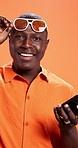 Surprise, smartphone and black man with sunglasses, upset and notification on orange studio background. African person, shocked and model with cellphone, wow and email scam with expression or emoji