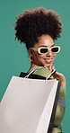 Woman, shopping bag and sunglasses in studio for smile, deal or sale for fashion by background. African person, happy and package for product, retail therapy or excited for discount with trendy style