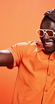 Studio, trendsetter and man with sunglasses, fashion or happy with stylish clothes, pride and color. Orange background, space and black person with eyewear, confident and trendy with unique outfit