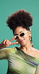 Face, peace sign and woman in studio, fashion and sunglasses on green background. Portrait, happy person and model with hand gesture, shades and eyewear with stylish clothes, creative and pride